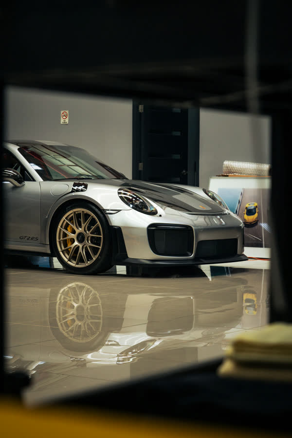 Porsche 911 GT2 RS plateado en un showroom oscuro